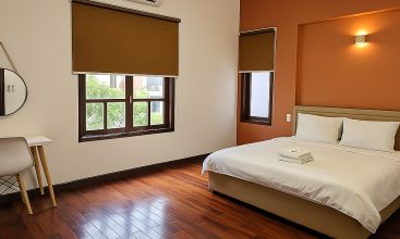 Exterior view of a spacious luxury 7-bedroom villa in Thao Dien, Ho Chi Minh City, featuring a large semi-indoor swimming pool, an elegant living room, a vibrant karaoke lounge with colorful lights, a comfortable king-size bedroom, and modern bathrooms (5 indoor, 3 outdoor).