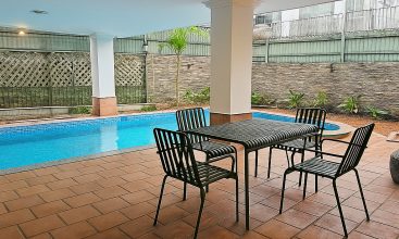 Exterior view of a spacious luxury 7-bedroom villa in Thao Dien, Ho Chi Minh City, featuring a large semi-indoor swimming pool, an elegant living room, a vibrant karaoke lounge with colorful lights, a comfortable king-size bedroom, and modern bathrooms (5 indoor, 3 outdoor).