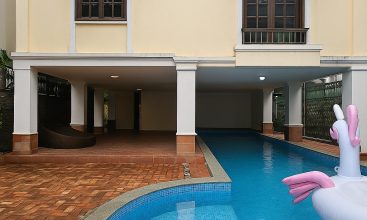 Exterior view of a spacious luxury 7-bedroom villa in Thao Dien, Ho Chi Minh City, featuring a large semi-indoor swimming pool, an elegant living room, a vibrant karaoke lounge with colorful lights, a comfortable king-size bedroom, and modern bathrooms (5 indoor, 3 outdoor).