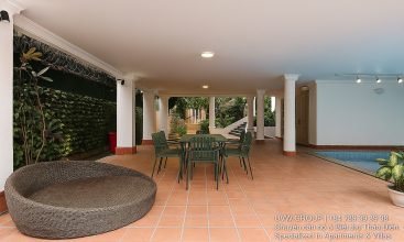 Exterior view of a spacious luxury 7-bedroom villa in Thao Dien, Ho Chi Minh City, featuring a large semi-indoor swimming pool, an elegant living room, a vibrant karaoke lounge with colorful lights, a comfortable king-size bedroom, and modern bathrooms (5 indoor, 3 outdoor).