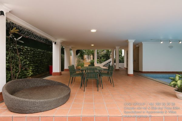 Exterior view of a spacious luxury 7-bedroom villa in Thao Dien, Ho Chi Minh City, featuring a large semi-indoor swimming pool, an elegant living room, a vibrant karaoke lounge with colorful lights, a comfortable king-size bedroom, and modern bathrooms (5 indoor, 3 outdoor).