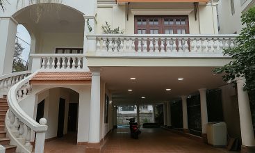 Exterior view of a spacious luxury 7-bedroom villa in Thao Dien, Ho Chi Minh City, featuring a large semi-indoor swimming pool, an elegant living room, a vibrant karaoke lounge with colorful lights, a comfortable king-size bedroom, and modern bathrooms (5 indoor, 3 outdoor).