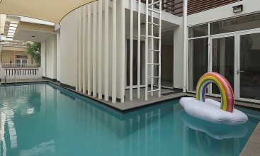 Exterior and interior views of a modern luxury 4-bedroom villa for rent in Thao Dien, Ho Chi Minh City, showcasing a stylish semi-indoor swimming pool, an open-plan living room with integrated karaoke and BBQ service area, a comfortable king-size bedroom, and 5 contemporary bathrooms (4 indoor, 1 outdoor).