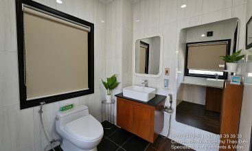 Exterior and interior views of a modern luxury 5-bedroom villa for rent in Thao Dien, Ho Chi Minh City, featuring a unique indoor swimming pool with wooden deck, a stylish living room, a dedicated karaoke room, a king-size bedroom, and 6 contemporary bathrooms (4 indoor, 2 outdoor).